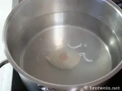 Ei in sanft verwirbeltes simmerndes Essig-Wasser gleiten lassen