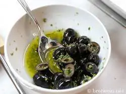 Oliven in Öl-Zitronen-Marinade mit Rosmarin ziehen lassen