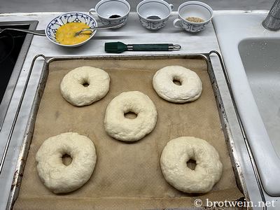 Gekochte Bagels auf Backpapier - Ei und Deko-Saaten lieben bereit